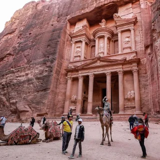 ヨルダン南部にある古代ナバテア人の都市、ペトラ遺跡にある宝物殿の前でラクダに乗る観光客（2022年12月12日撮影）。Photo: AFP via Getty Images