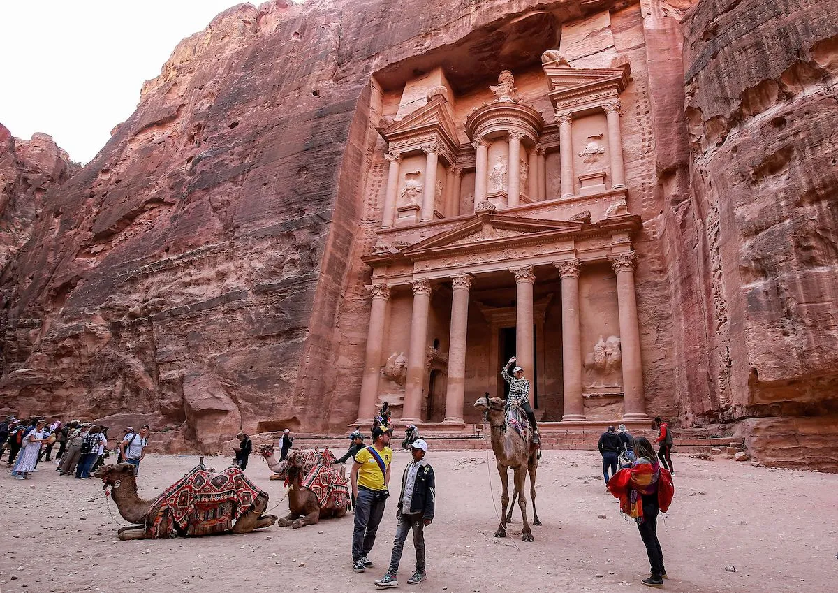 ヨルダン南部にある古代ナバテア人の都市、ペトラ遺跡にある宝物殿の前でラクダに乗る観光客（2022年12月12日撮影）。Photo: AFP via Getty Images