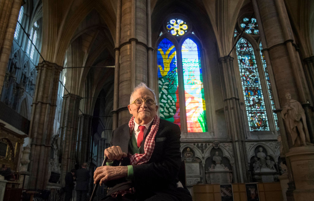 ウェストミンスター寺院のステンドグラス、《The Queen's Window》の前でポーズをとるデイヴィッド・ホックニー。Photo: Victoria Jones - WPA Pool/Getty Images